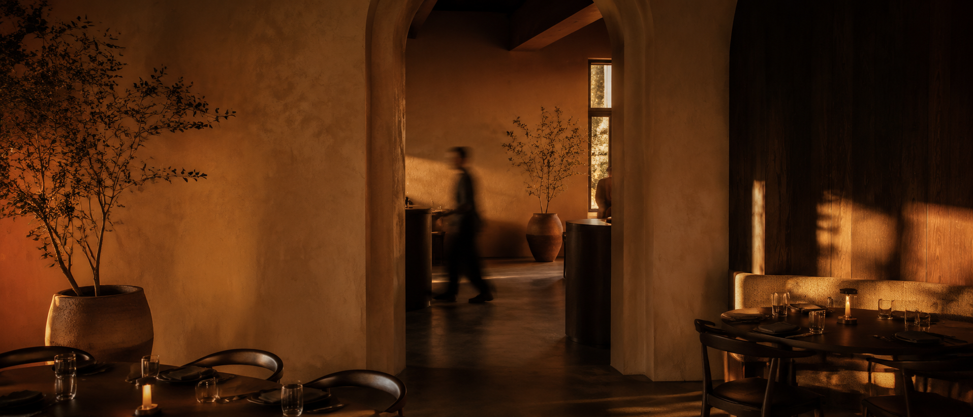 Fictional amber-lit contemporary dining interior with an anonymous blurred figure